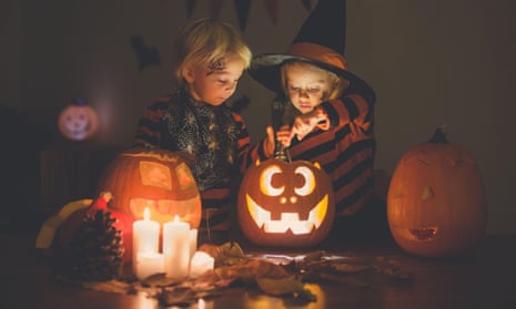 Adorable children, toddler boy and girl, playing with Halloween carved pumpkin and decoration at home2C0RR18 Adorable children, toddler boy and girl, playing with Halloween carved pumpkin and decoration at home
