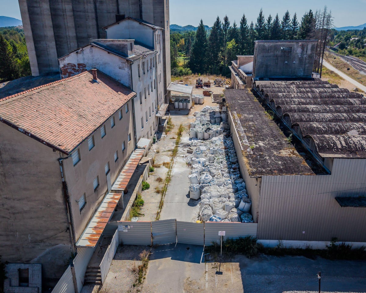 An aerial photograph of a warehouse complex, where piles of rubbish bags can be seen scattered along the ground.