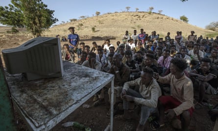 Men who fled the conflict in Tigray watch the TV news at Umm Rakouba refugee camp in Qadarif, eastern Sudan