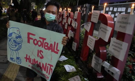 Indonesia has a huge passion for football but is no stranger to tragedy | Soccer 5 A man holds a poster during a candle light vigil for the victims of the tragedy in Indonesia