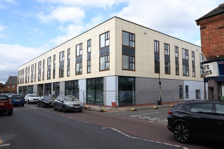 A box-shaped three-storey building with temporary fencing around it