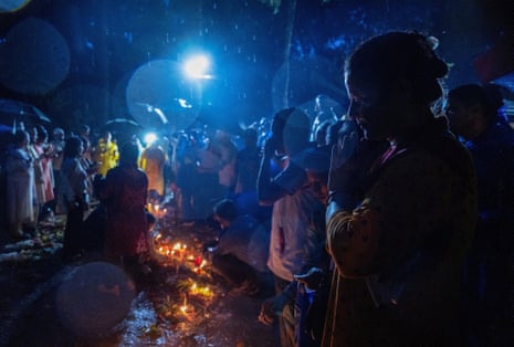 people pray at a mass burial site