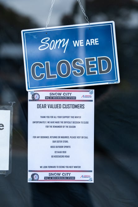A sign in the window of Snow City Ski Hire in Jindabyne explains why they have closed early in the ski season due to the lack of natural snow and visitors.