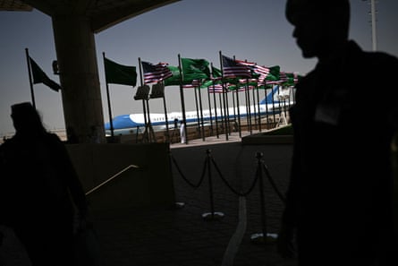 American and Saudi Arabian flags flying with two silhouette people in the foreground