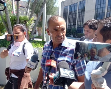 A man surrounded by people pointing microphones and phones at him