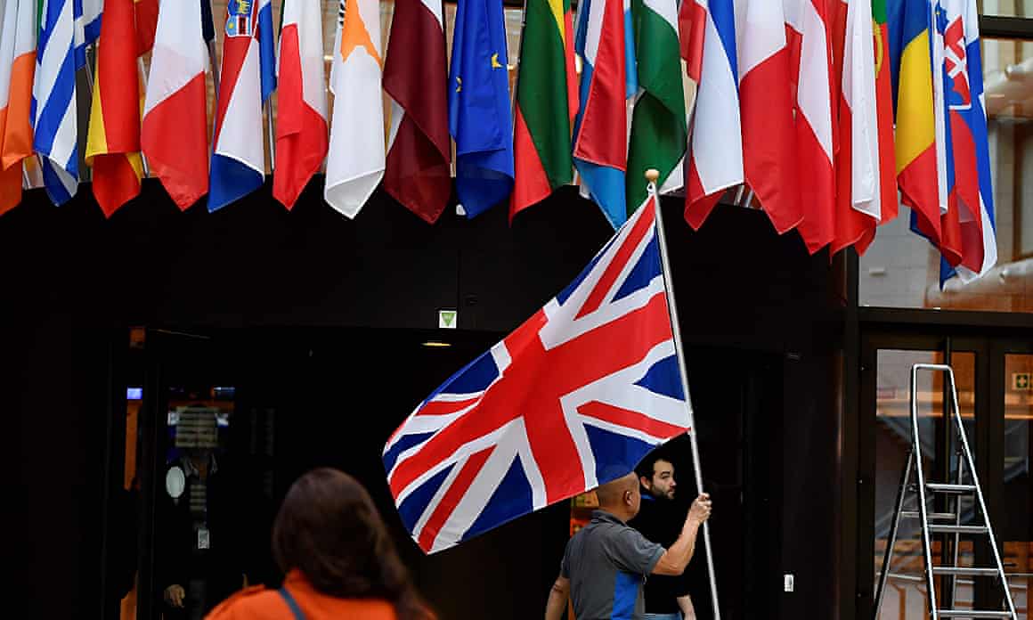 An employee holds a Union Jack at the entrance of Consilium building at the EU headquarters in Brussels