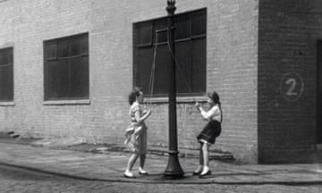 Two girls on a swing attached to a lamp-post