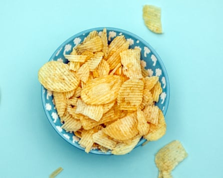 Top view of potato chips in a blue bowl on a blue background
