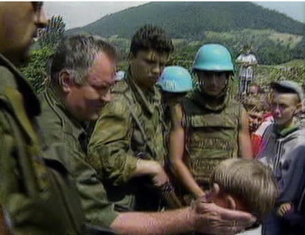Mladić, standing alongside other Bosnian Serb troops, pats a boy's cheek