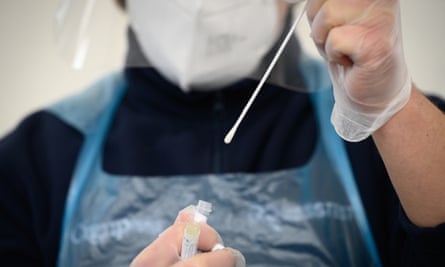 A member of the medical team holds up a used swab from a PCR test