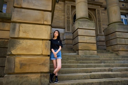 A young Chinese woman standing on the steps of a grand neo-classical town hall