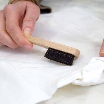 close-up of person rubbing stain brush on white piece of fabric