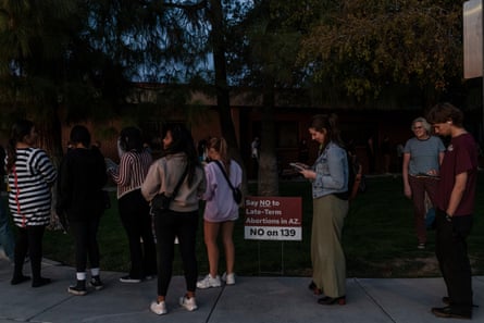 people stand in line next to a sign that reads ‘say no to late term abortions in AZ no on 139’