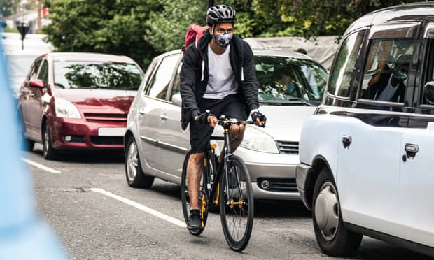 A cyclist rides through traffic in London