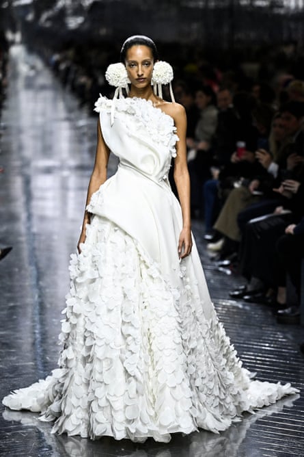 A woman of colour wearing a white heavily decorated wedding gown.