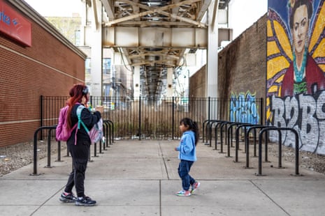 a woman and girl outside under a subway track