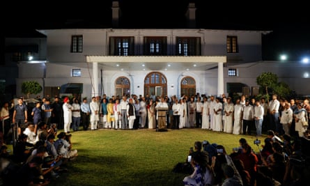 Mallikarjun Kharge speaking to media on the lawn of a white mansion house while surrounded by party members and supporters