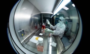 A lab technician wearing Personal Protective Equipment (PPE) performs tests under a hood, using reagent bottles at a French pharmaceutical company Sanofi’s laboratory in Val de Reuil.