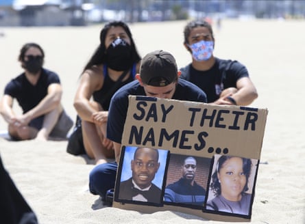 People sit during a moment of silence at a Black Lives Matter protest, in the Venice Beach area of Los Angeles, 12 June 2020.