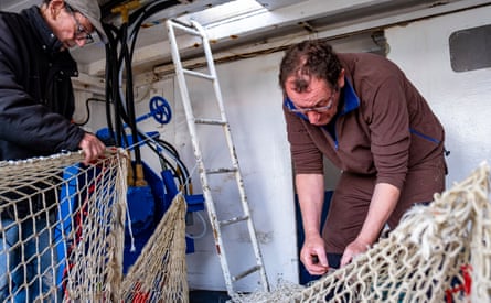 Two men tend to nets on a fishing boat