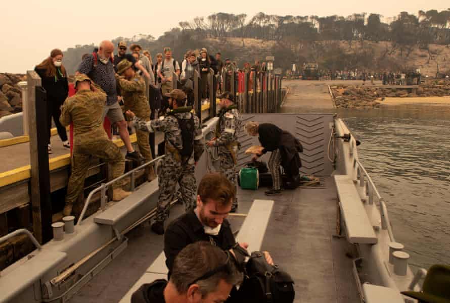 People fleeing the fires at Mallaccota board an Australian navy landing craft to be evacuated.