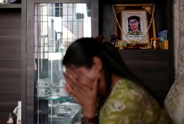Rachana Khatiwada cries, while a photo of her son is displayed in the background of her home