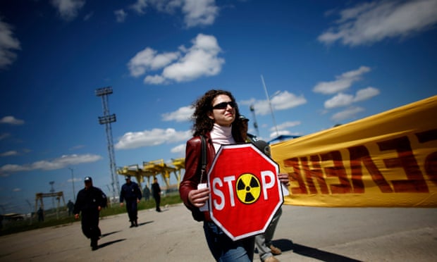 An anti-nuclear demonstrator protests outside the gates of a plant.