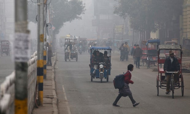 A schoolgirl crosses a road shrouded in haze in New Delhi, India