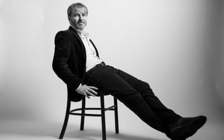 Garrett Carr posing for a studio portrait sitting on a chair with legs outstretched.