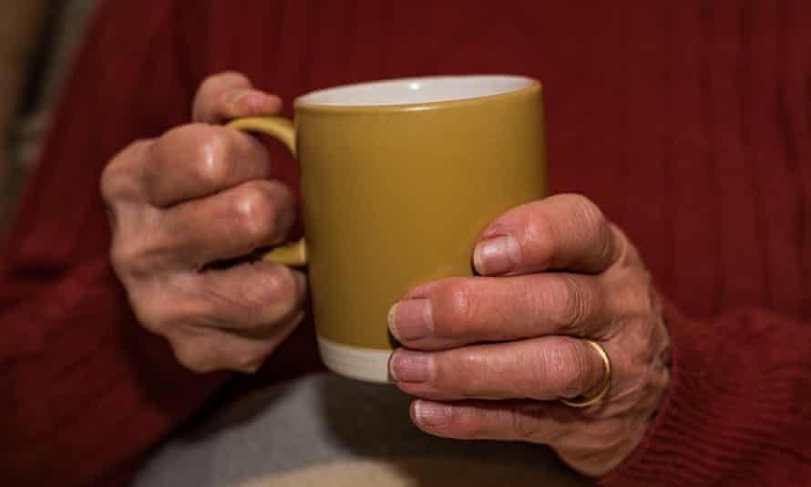 An older lady’s hands holding a mug of tea.