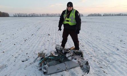 A police officer stands next to a part of a Russian cruise missile shot down in the Kyiv region.