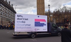 A van bearing an ad billboard with a message from Cancer Research UK urging MPs to back the bill passes through Westminster: the message says 'MPs, don't let smoke cloud your judgment'