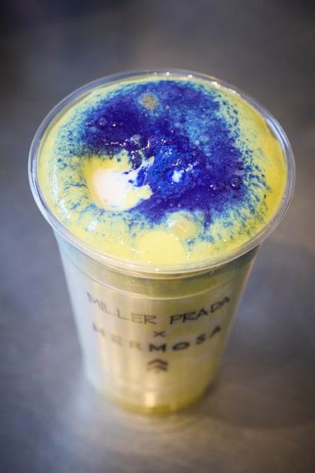 A yellow drink topped by blue spirulina, in a plastic cup