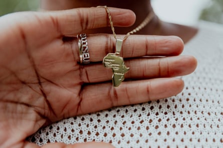A hand holding a necklace with a pendant in the shape of Africa