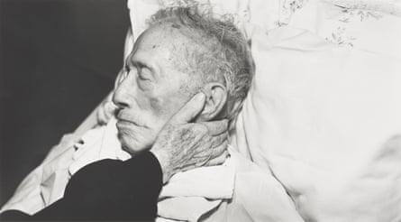 a woman’s hand holding an older man’s face as he rests