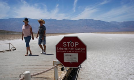 people walk past sign in death valley warning about extreme heat danger