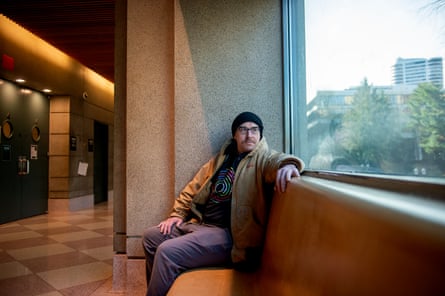 A man sits for a portrait on a leather bench