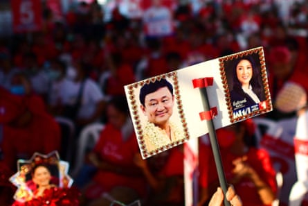 A Pheu Thai Party supporter holding a placard with photographs of former Thai prime ministers Thaksin Shinawatra and Yingluck Shinawatra.