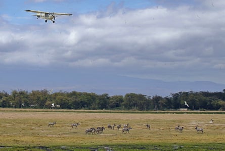 Aircraft flies over a herd of zebra at Amboseli National Park, Kenya