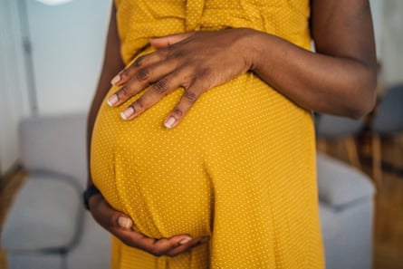 Pregnant woman in a yellow dress hold her stomach