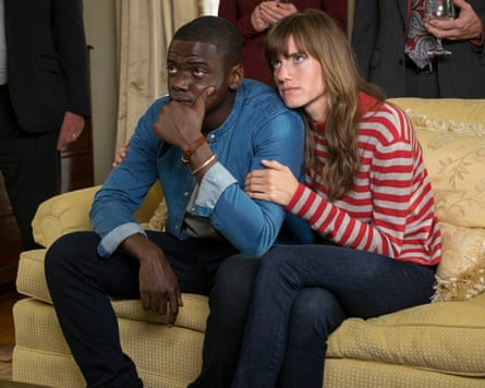 Daniel Kaluuya and Allison Williams sitting closely on a sofa in a scene from Get Out