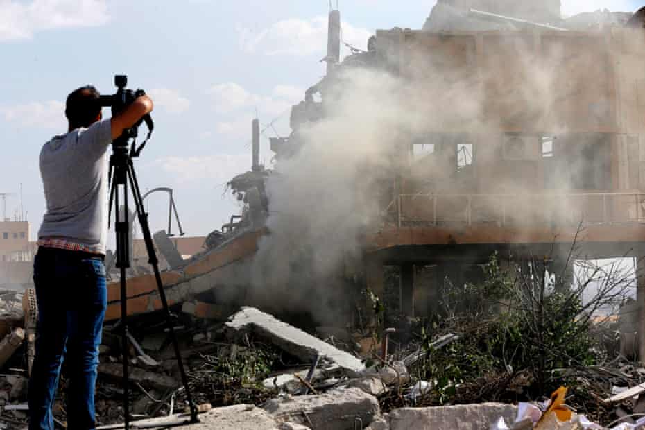 A journalist films the wreckage of the Scientific Studies and Research Centre in Barzeh, southern Syria in 2018.