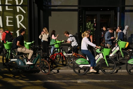 People getting on Lime and Forest hire bikes in Tottenham Court Road.