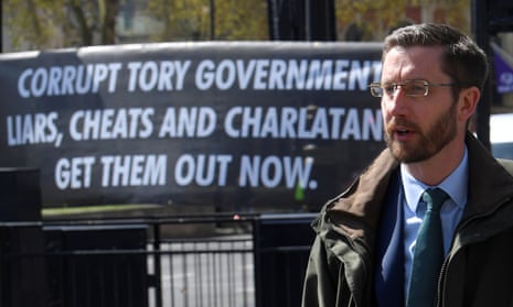 Simon Case in front of a banner reading ‘Corrupt Tory government – liars, cheats and charlatans – get them out now.’