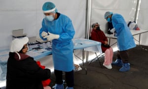 Healthcare workers wearing personal protective equipment (PPE) give instructions before taking a swab sample from women for the rapid coronavirus disease (COVID-19) antigen test outside the Azteca Stadium in Mexico City, Mexico, November 25, 2020.