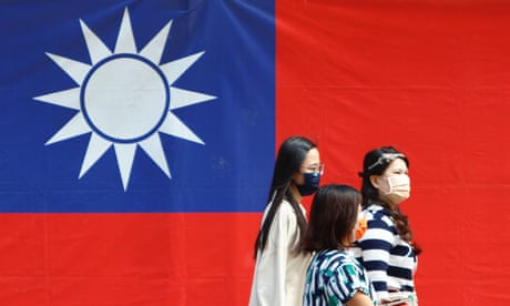 People walk in front of a Taiwan flag