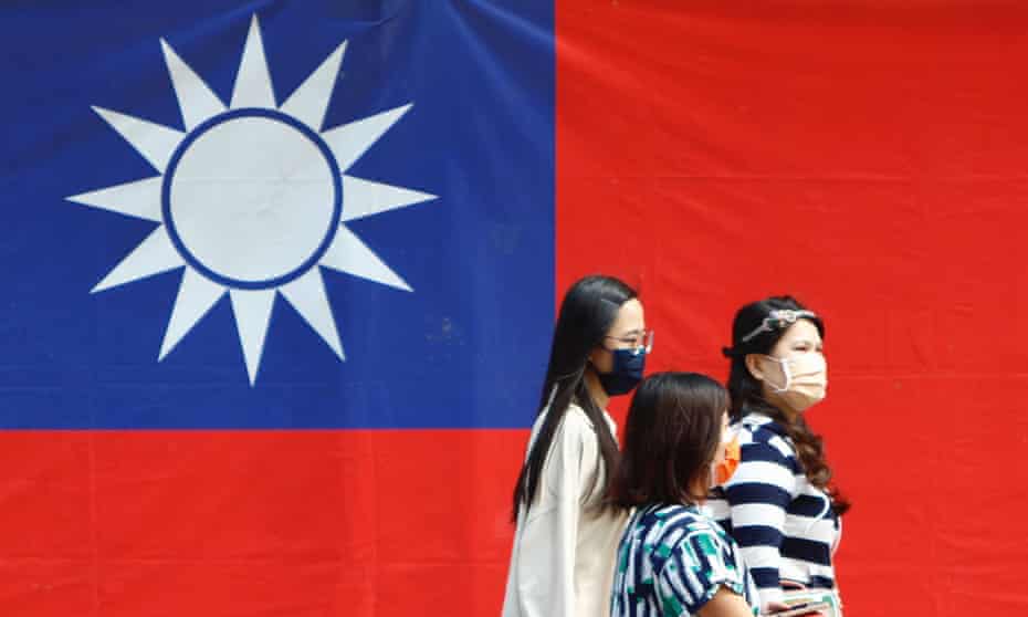 People walk in front of a Taiwan flag