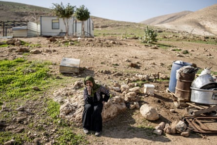 A woman sits alone, crying, in a rural setting