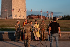 People pose for a photo with National Guard troops at the Washington Monument.