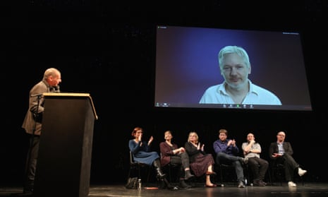 Yanis Varoufakis (left) looks on as Julian Assange speaks via a live broadcast at the official launch of DiEM25.